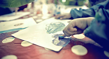 Vergrößerungsansichten für Bild: Nahaufnahme: In einer Kindertageseinrichtung malen Kinderhände mit Fingerfarbe ein Bild